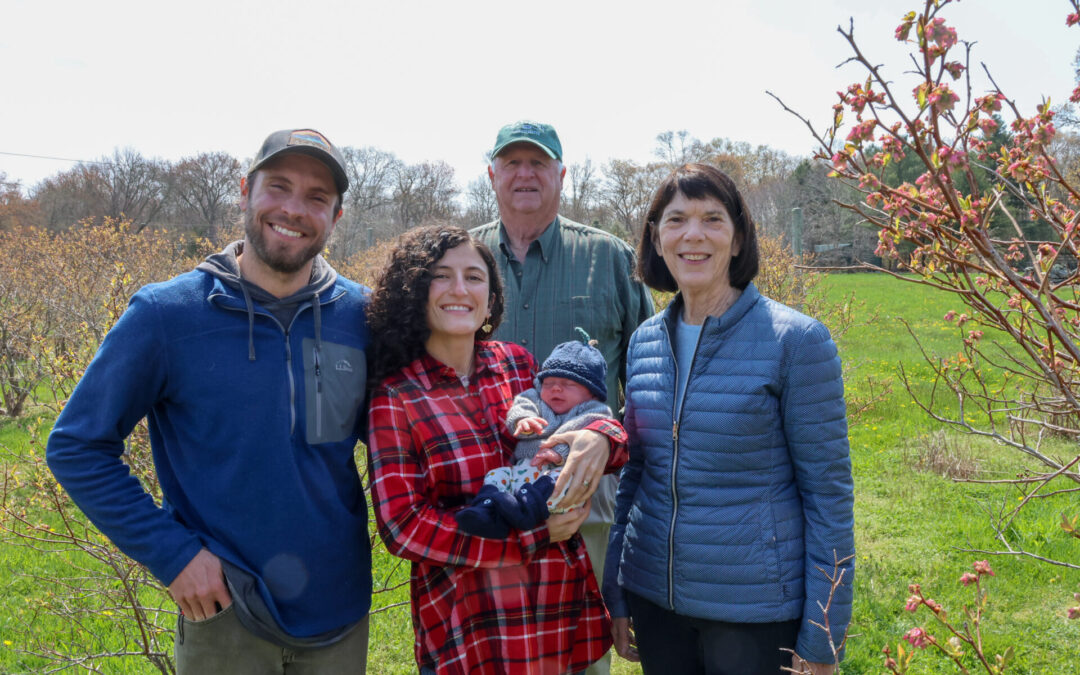 smiling adults with baby at blueberry farm